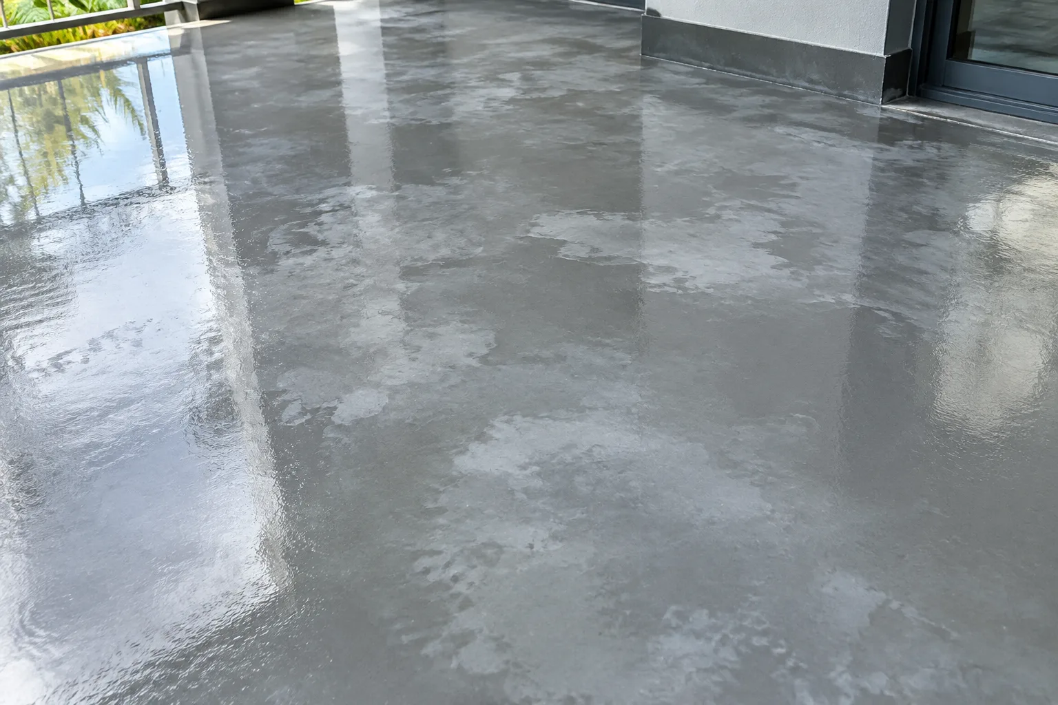 Grey epoxy floor marred by cloudy, milky patches across an otherwise glossy surface