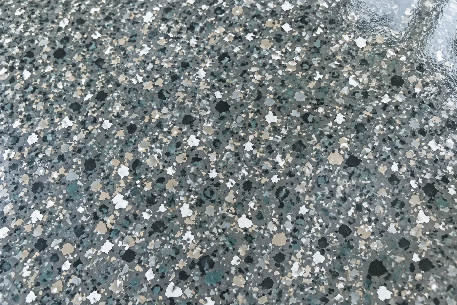Close view of dense charcoal, grey, sand and white flakes under a gloss coat